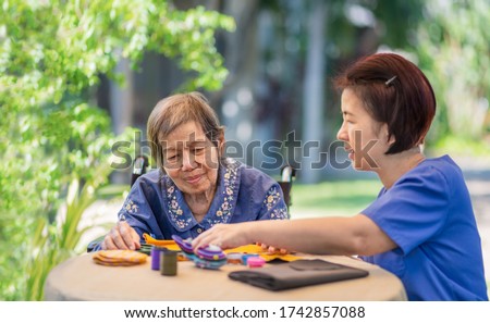 Elderly woman with caregiver in the needle crafts occupational therapy  for Alzheimer’s or dementia Royalty-Free Stock Photo #1742857088