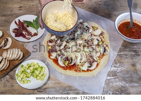 Chef hands making homemade pizza dough and preparing with tomato, mushrooms, ham, mozzarella and parmesan cheese.Italian food