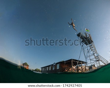 man jumping from tower to lake water