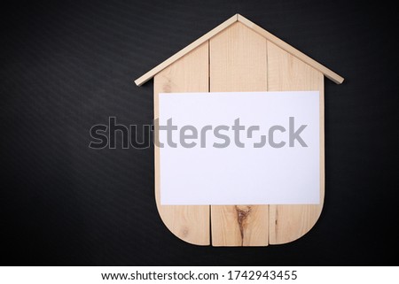 Blank Wood House with blank paper on black background. Concept sale, construction of ecological houses and discounts.