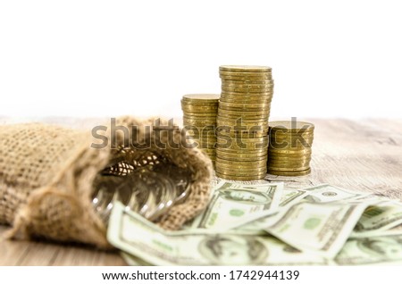 Stacks of gold coins and a bag of dollars on a white background. concept of savings, taxes or economy.