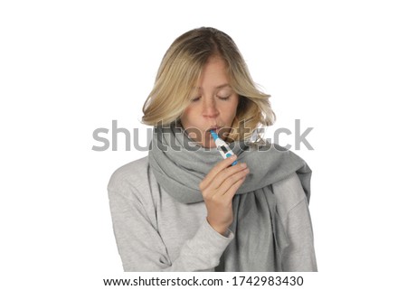 Young woman looks at a fever thermometer in her mouth