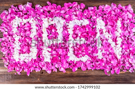 A rectangle of white and pink rose petals with stylized Open word on wooden background