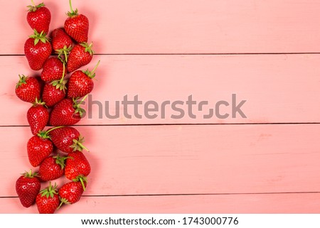 Ripe red strawberries on a pink wooden background