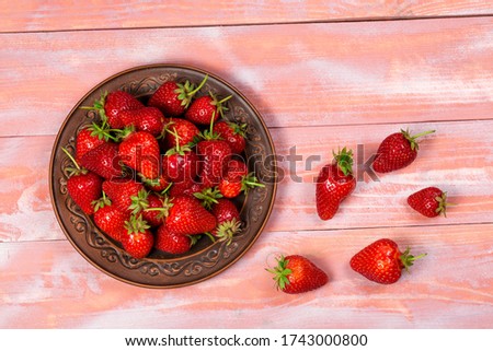 Ripe red strawberries on a pink wooden background