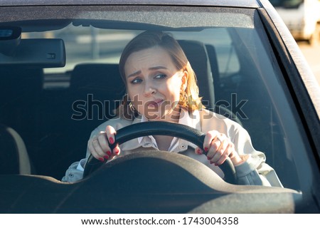 Woman drives her car for the first time, tries to avoid a car accident, is very nervous and scared, worries, clings tightly to the wheel. Inexperienced driver in stress and confusion after an accident Royalty-Free Stock Photo #1743004358