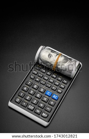calculator and a roll of us dollarts on desk.