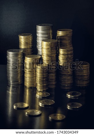 Piles of coins of various denominations on a black background. Investments and Savings