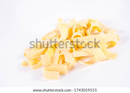 Raw pappardelle pasta on a white background