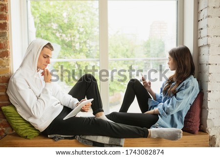 Online talks, shopping. Quarantine lockdown, stay home concept - young beautiful caucasian couple enjoying new lifestyle during coronavirus worldwide emergency. Happiness, togetherness, healthcare. Royalty-Free Stock Photo #1743082874