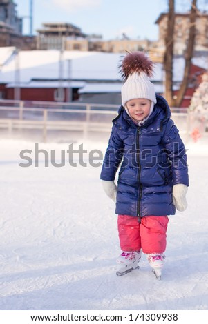 Adorable little girl in the skate on white ice