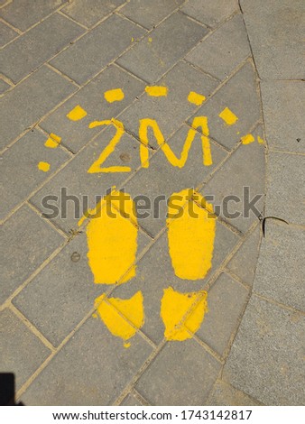  legs in yellow foot symbol on street tile for social distance of 2 meters during coronavirus 2020