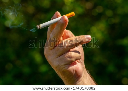 Cigarette in the hand of an old man close up, picture for design