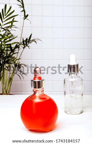 Two bottles of essence, serum or care oil in the bathroom against a palm tree. The concept of face and body skin care, aromatherapy.
