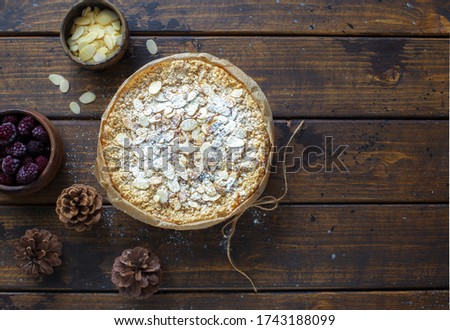 Grated rustic pie with ricotta, berries and almond flakes on dark wooden background. Flat lay