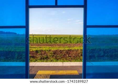 Abstract window made of blue plastic with a view of the field. Exit to the veranda.