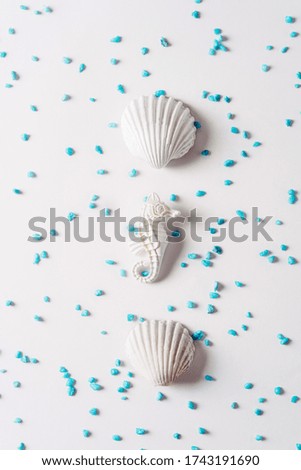 sea shell and seahorse in white color surrounded by small turquoise blue stones on bright background, Summer concept.