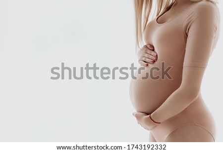 Pregnant woman holding her pregnancy tummy with love - motherhood maternity close up photo
