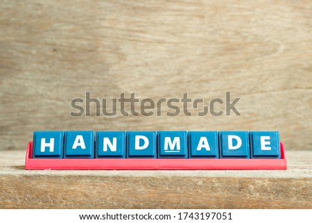 Tile letter on red rack in word handmade on wood background