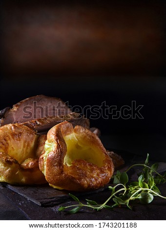 Traditional British Yorkshire puddings served with prime roast beef and thyme herb garnish. Shot against a rustic background with copy space.