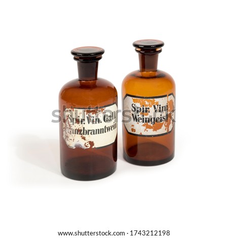Historic brown medicine glass bottles with vintage and used labels isolated on white background. Translation of label texts “spiritus vinum gallum rubbing alcohol“ and „spiritus vini spirit of wine".