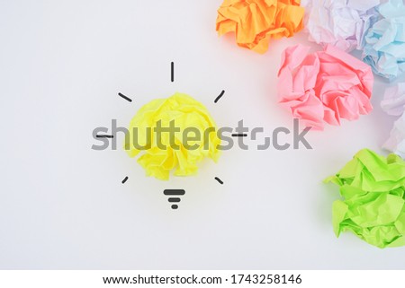 Come up with a creative idea. Crumpled paper symbolizing various solutions with one highlighted as a light bulb as the correct one.
