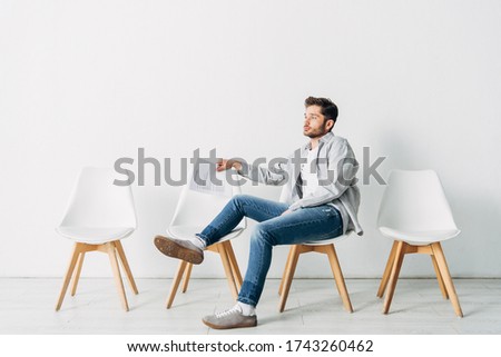 Side view of man with resume sitting on chair in office