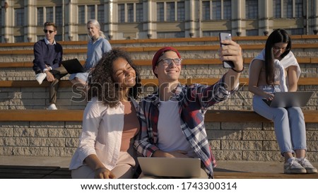 Group of students in front of university taking selfie.