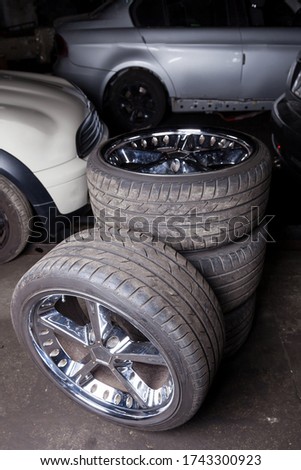A set of stylish tuned wheels with shiny chrome disks folded into the composition against the background of cars in the workshop for seasonal replacement at tire service. Royalty-Free Stock Photo #1743300923