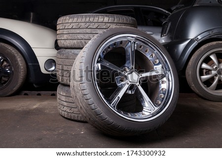 A close-up of beautiful fashionable wheels for a car, three folded on top of each other and one in first place with a shiny chrome disks for sale in service. Royalty-Free Stock Photo #1743300932