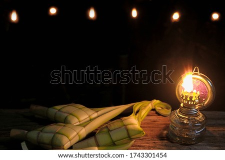 Close-up of oil lamp and ketupats against black background