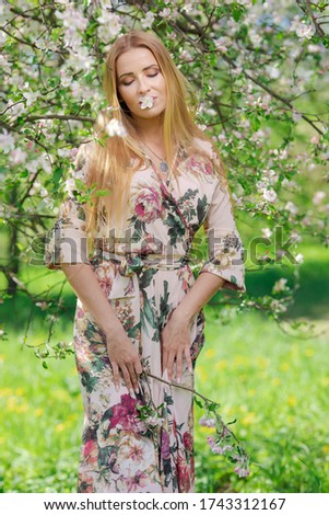 Blond girl with long hair in spring blooming apple orchard