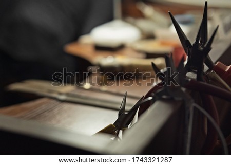 Working desk for craft jewelery making with professional tools. Workplace with hand tools. Silhouette of pliers on a desktop background. Working environment. A lot of pliers.