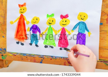 Little girl is drawing the children with words Children's Day on a wooden easel for the holiday Happy Children's Day.