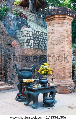Buddhist altar with candles and bananas and flowers on table in temple with red bricks