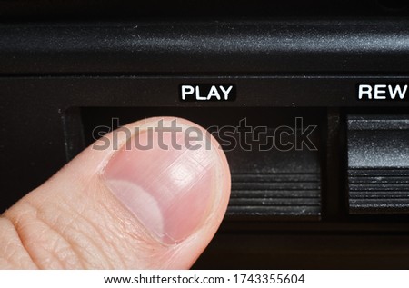 Finger pressing the play button on cassette player
