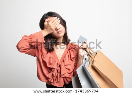 Unhappy  young Asian woman with shopping bags and credit card on white background Royalty-Free Stock Photo #1743369794