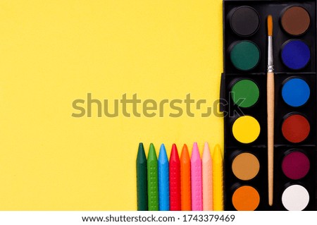 Creativity concept. Paints and crayons on a yellow background. Copy space. Banner