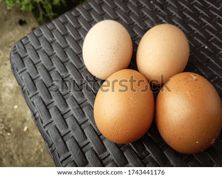 4 Fresh chicken eggs with different color gradations on a brown woven background