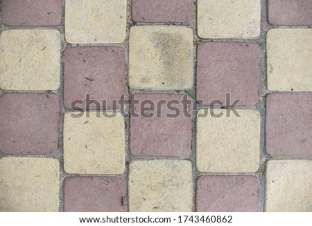 Top view of the red and yellow pavement background. Full frame of regular square cobbles in lines