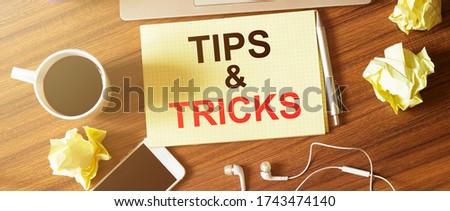 Table with cup of coffee, phone, headphones and paper. TIPS AND TRICKS text