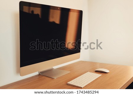 Modern desktop computer with wireless keyboard and mouse on light wooden table. Home office concept. Workplace order. Minimalist interior with white walls