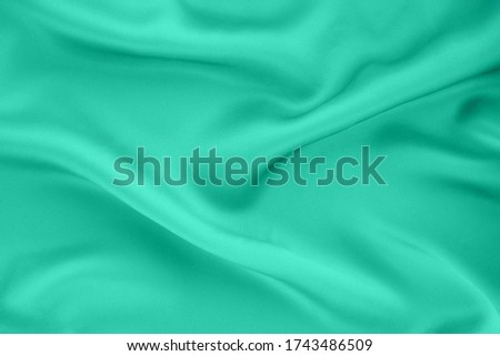 The texture of draped silk fabric. Biscay green, cyan, quiet wave background. Trend colors concept.