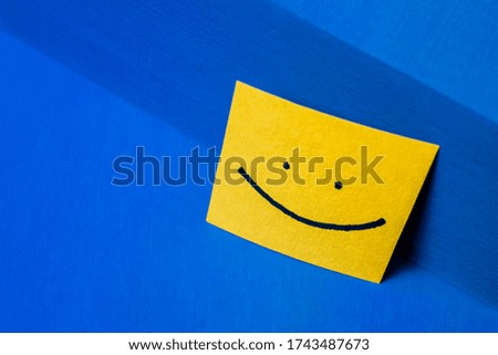Happy face illustrated on yellow paper notes and blue background