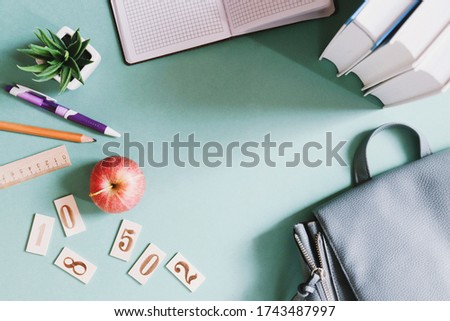 Back to school flat lay composition photography. Books, stationery, backpack and red apple on a green table. Education concept