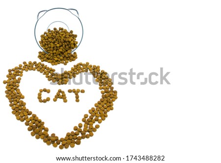 The word "CAT" and a heart written by cat food near transparent bowl with ears on white studio background. Pets care. Nutrition and veterinary concept. Copy space. 