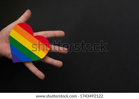 the rainbow heart lgbt in hands on a black background