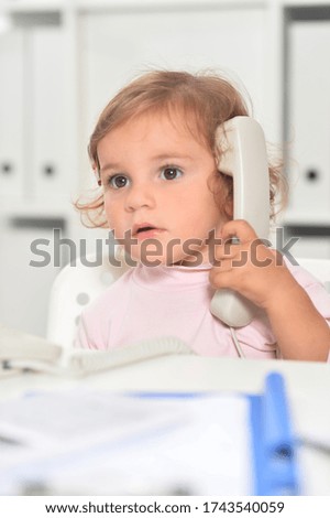 Portrait of cute little girl using phone in office