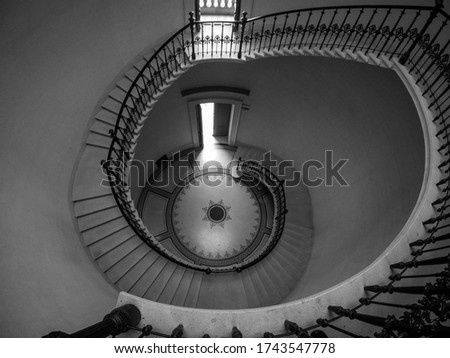 Black and white spiral staircase with the open door downstairs, view from above. Freedom concept.