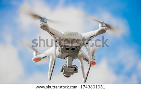 A bottom up view of a drone taking off with its propellers at maximum speed
